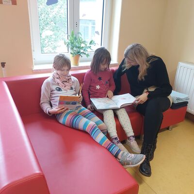 Bild vergrößern: Zwei Kinder lesen mit pädagogischer Fachkraft